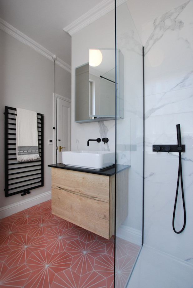 Inspiration for a small modern shower room bathroom in London with light wood cabinets, a walk-in shower, a wall mounted toilet, porcelain tiles, grey walls, terracotta flooring, a vessel sink, marble worktops, pink floors, an open shower, black worktops and multi-coloured tiles.