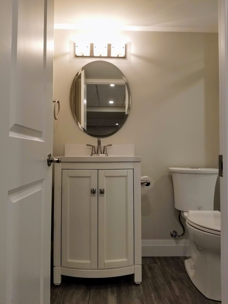 Cette photo montre une grande salle d'eau chic avec un placard avec porte à panneau encastré, des portes de placard blanches, WC à poser, un sol en vinyl, un sol marron, un plan de toilette blanc, meuble simple vasque et meuble-lavabo encastré.