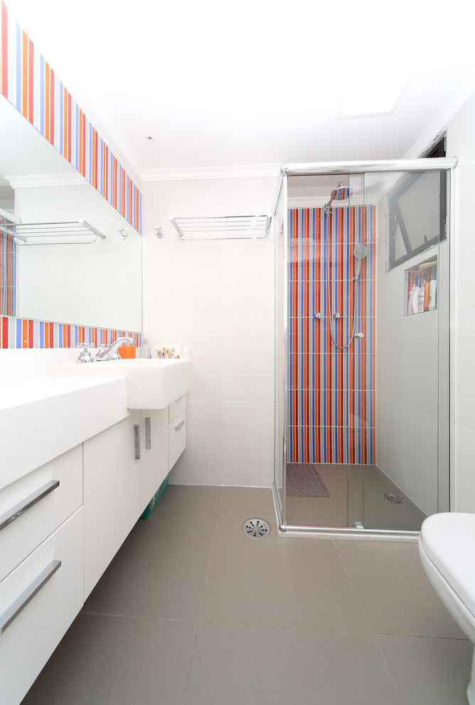 На фото: детская ванная комната в современном стиле с плоскими фасадами, белыми фасадами, душем в нише и разноцветной плиткой