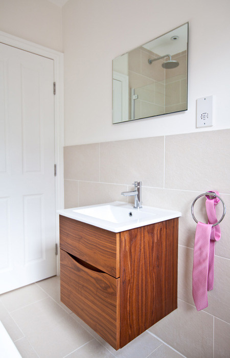 Inspiration for a medium sized contemporary family bathroom in London with an integrated sink, dark wood cabinets, a built-in bath, a shower/bath combination, a one-piece toilet, grey tiles, porcelain tiles, white walls and porcelain flooring.