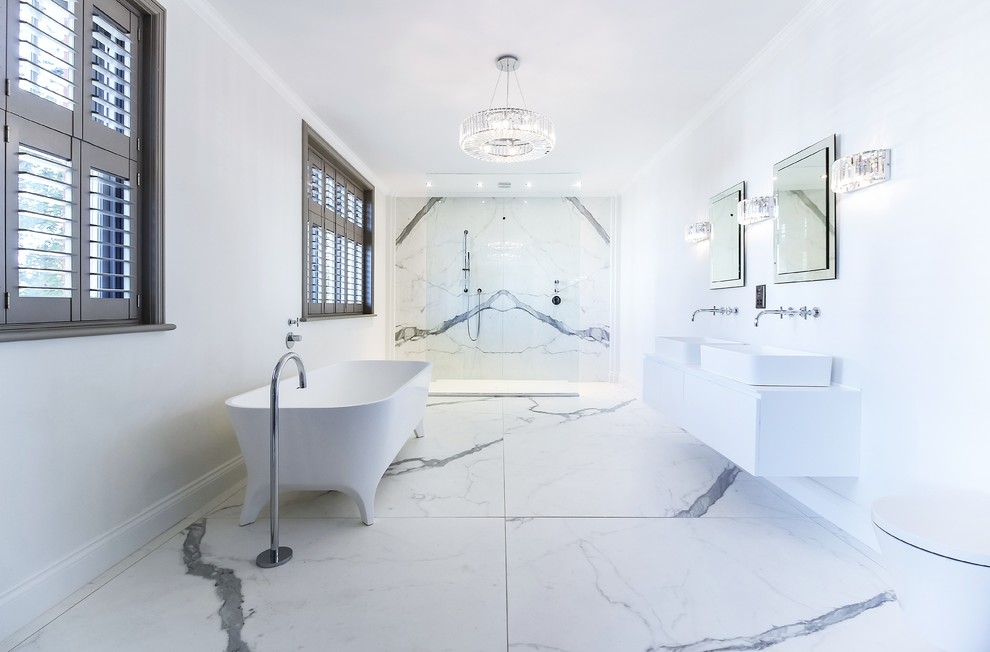 Пример оригинального дизайна: огромная главная ванная комната в современном стиле с плоскими фасадами, белыми фасадами, отдельно стоящей ванной, открытым душем, унитазом-моноблоком, черно-белой плиткой, мраморной плиткой, белыми стенами, мраморным полом, подвесной раковиной, мраморной столешницей, белым полом, открытым душем и белой столешницей