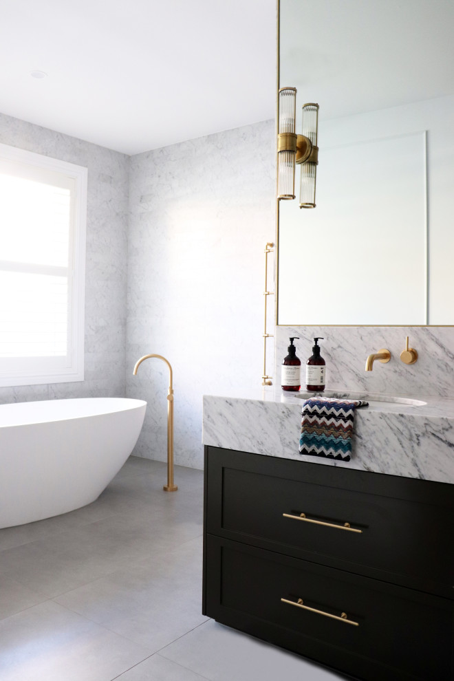 Klassisk inredning av ett stort grå grått en-suite badrum, med luckor med infälld panel, ett fristående badkar, våtrum, grå kakel, keramikplattor, grå väggar, klinkergolv i keramik, ett undermonterad handfat, marmorbänkskiva, grått golv och med dusch som är öppen