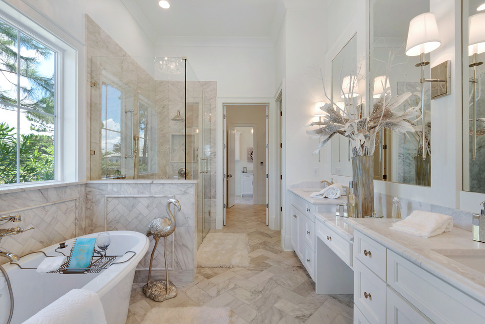 Photo of a large coastal ensuite bathroom in Miami with recessed-panel cabinets, white cabinets, a freestanding bath, an alcove shower, grey tiles, white tiles, stone slabs, white walls, marble flooring, a submerged sink and marble worktops.