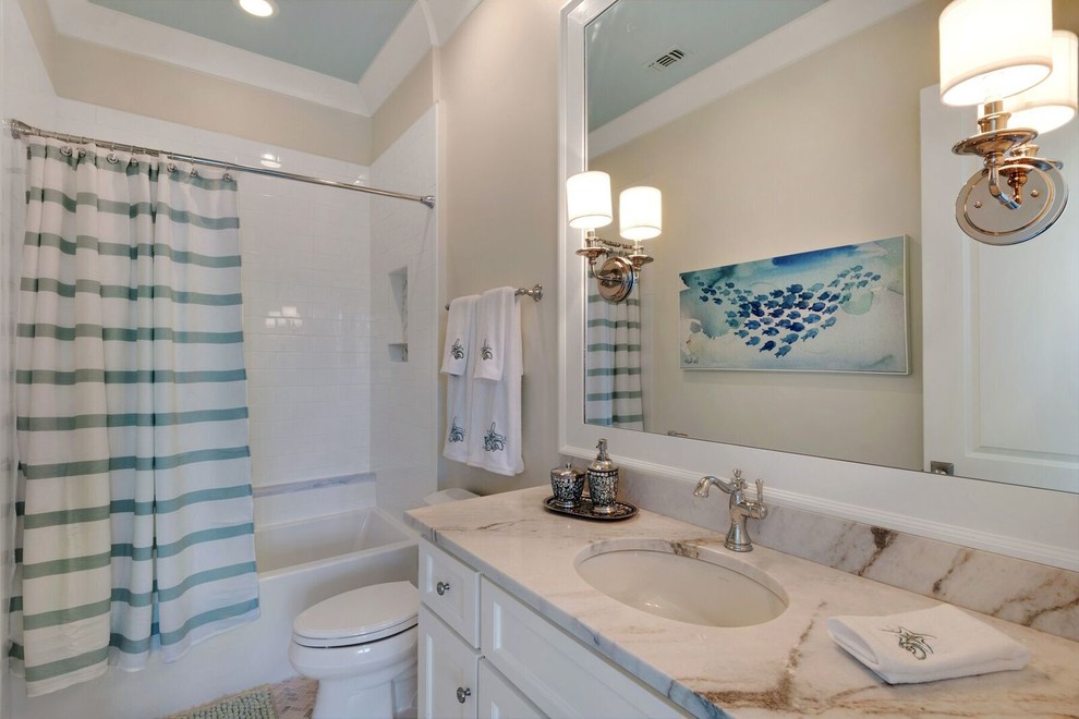 Cette image montre une salle de bain marine de taille moyenne avec un placard avec porte à panneau encastré, des portes de placard blanches, une baignoire en alcôve, un combiné douche/baignoire, WC séparés, un carrelage blanc, un carrelage métro, un mur beige, un lavabo encastré et un plan de toilette en marbre.