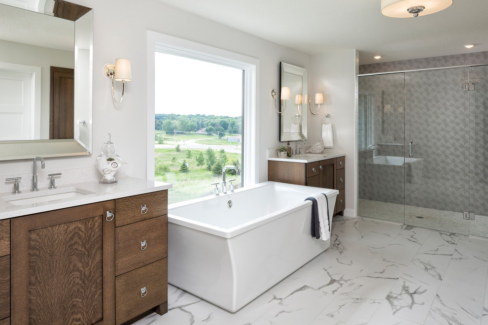 Cette image montre une salle de bain principale traditionnelle en bois foncé avec une baignoire indépendante, une douche à l'italienne, un carrelage gris, un mur blanc, un sol en marbre, un lavabo encastré, un sol blanc, une cabine de douche à porte battante, un plan de toilette blanc et un placard à porte shaker.