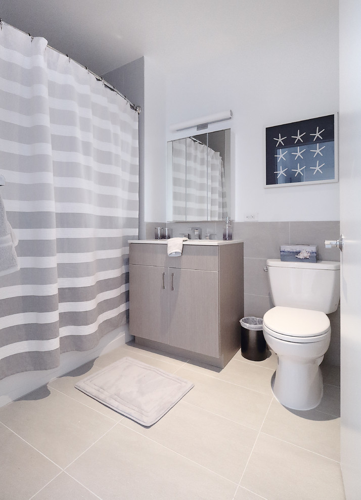 Inspiration pour une salle d'eau design de taille moyenne avec un placard à porte plane, des portes de placard grises, une baignoire en alcôve, un combiné douche/baignoire, WC séparés, un carrelage gris, des carreaux de porcelaine, un mur blanc, un sol en carrelage de porcelaine, un lavabo encastré, un plan de toilette en surface solide, un sol gris, une cabine de douche avec un rideau et un plan de toilette blanc.