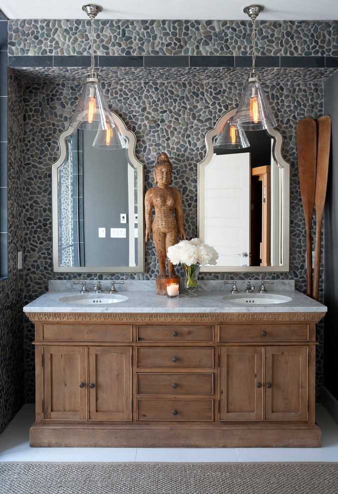 Imagen de cuarto de baño costero con lavabo bajoencimera, armarios estilo shaker, encimera de mármol, suelo de baldosas tipo guijarro, paredes grises y puertas de armario de madera en tonos medios