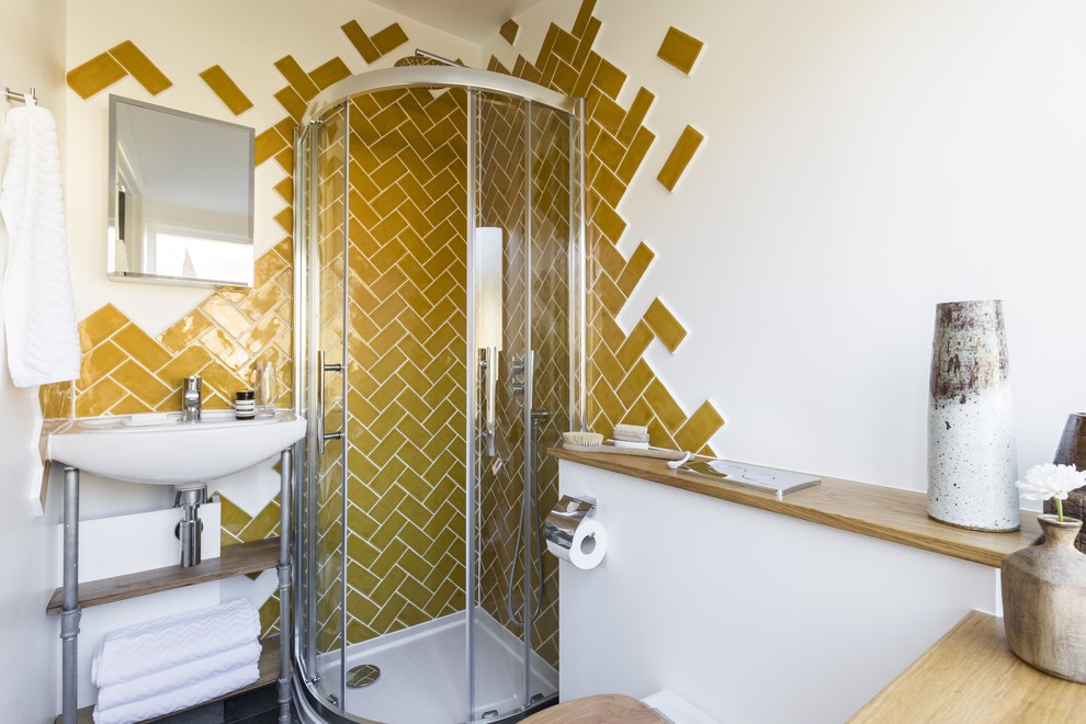Inspiration for a small contemporary ensuite bathroom in London with open cabinets, light wood cabinets, a corner shower, a wall mounted toilet, yellow tiles, ceramic tiles, white walls, concrete flooring and a wall-mounted sink.