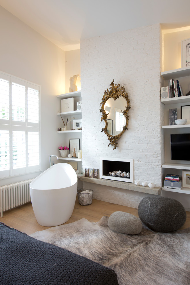Medium sized contemporary bathroom in London with a freestanding bath, white walls, light hardwood flooring and a chimney breast.