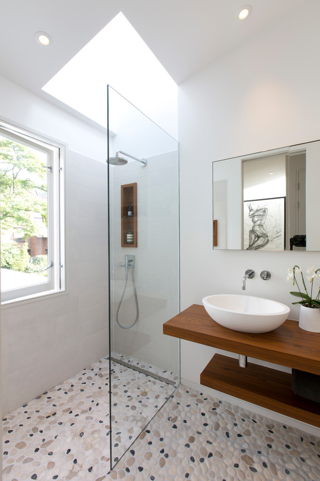 Kleines Modernes Duschbad mit offenen Schränken, grauen Fliesen, grauer Wandfarbe, Aufsatzwaschbecken, Waschtisch aus Holz, buntem Boden, offener Dusche, brauner Waschtischplatte, offener Dusche und Kiesel-Bodenfliesen in London