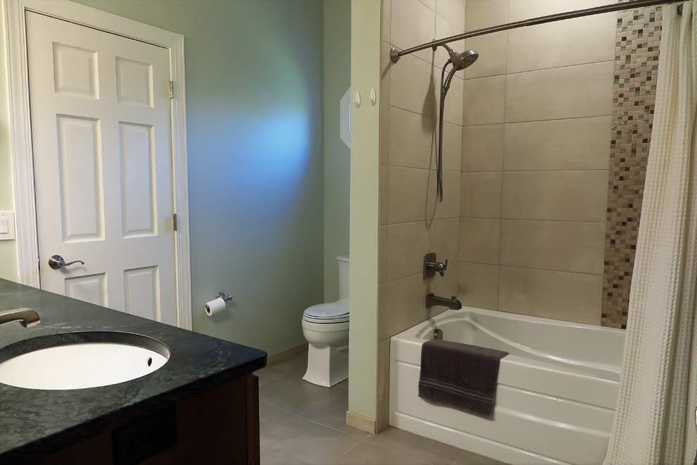 Inspiration for a medium sized traditional ensuite bathroom in Minneapolis with shaker cabinets, brown cabinets, an alcove bath, a two-piece toilet, beige tiles, ceramic tiles, green walls, ceramic flooring, a submerged sink, soapstone worktops, grey floors, a shower curtain and green worktops.