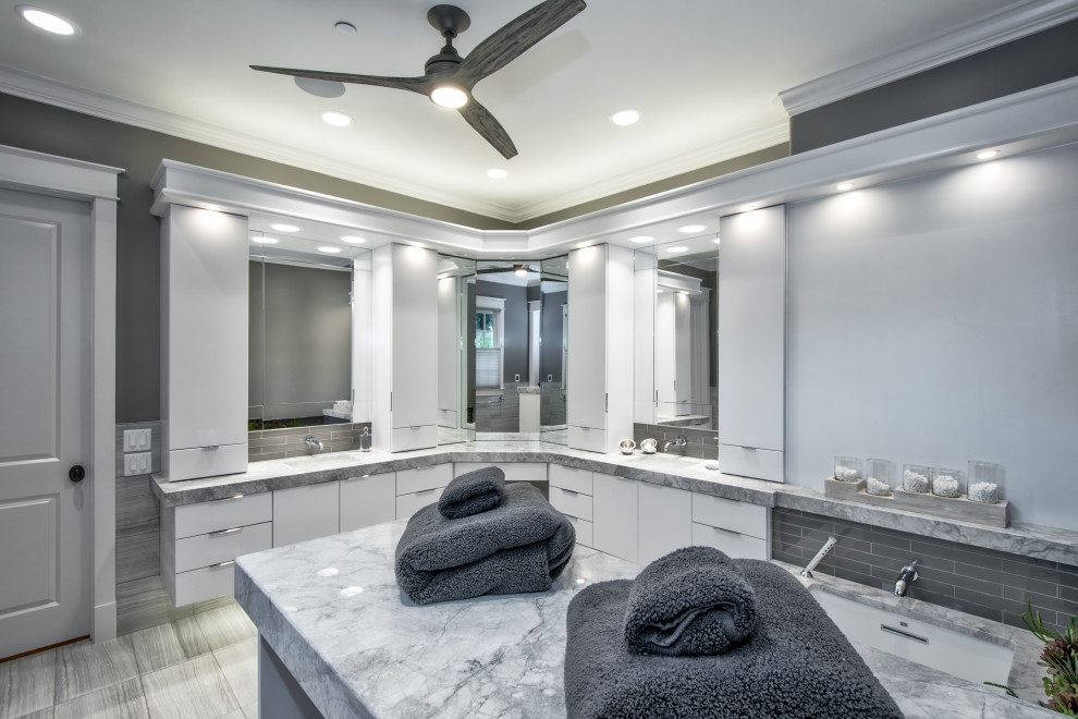 Exempel på ett stort modernt grå grått en-suite badrum, med luckor med upphöjd panel, vita skåp, ett undermonterat badkar, en kantlös dusch, en toalettstol med hel cisternkåpa, grå kakel, glaskakel, grå väggar, klinkergolv i porslin, ett undermonterad handfat, bänkskiva i kvartsit, grått golv och dusch med skjutdörr