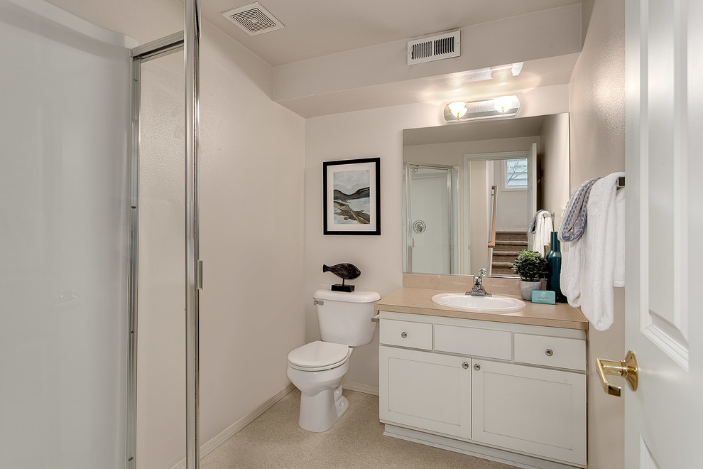 Exempel på ett litet klassiskt badrum med dusch, med skåp i shakerstil, vita skåp, en toalettstol med separat cisternkåpa, beige kakel, gula väggar, linoleumgolv, ett nedsänkt handfat och bänkskiva i akrylsten