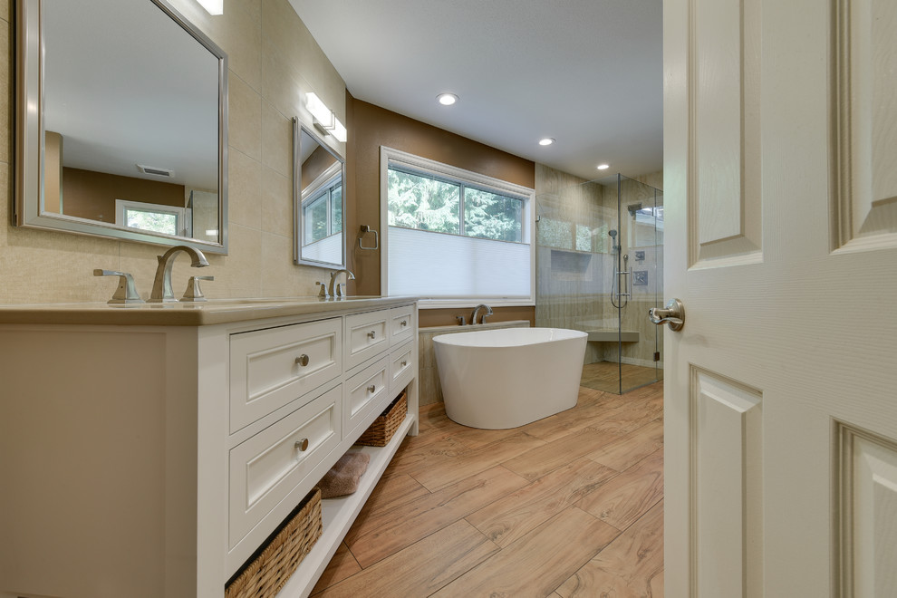 Klassisk inredning av ett stort en-suite badrum, med luckor med infälld panel, beige skåp, ett fristående badkar, en kantlös dusch, beige kakel, porslinskakel, bruna väggar, klinkergolv i porslin, ett undermonterad handfat, bänkskiva i kvarts, brunt golv och dusch med gångjärnsdörr