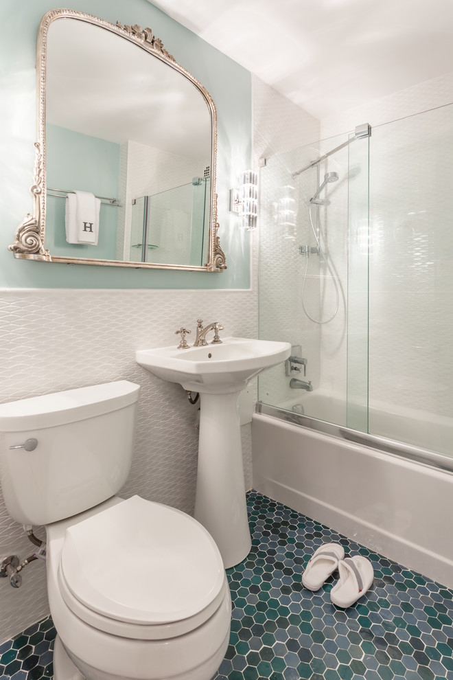 Design ideas for a small classic ensuite bathroom in New York with flat-panel cabinets, blue cabinets, a built-in bath, a shower/bath combination, a two-piece toilet, multi-coloured tiles, mosaic tiles, white walls, mosaic tile flooring and a pedestal sink.