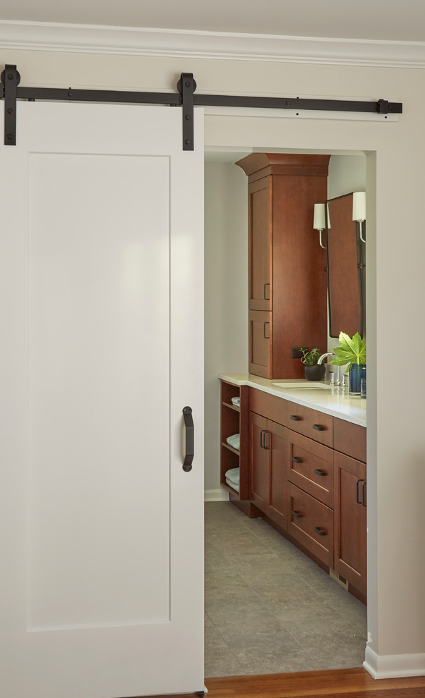 Medium sized traditional ensuite bathroom in Chicago with shaker cabinets, medium wood cabinets, an alcove bath, a shower/bath combination, a two-piece toilet, white tiles, metro tiles, grey walls, porcelain flooring, a submerged sink, engineered stone worktops, grey floors and a shower curtain.