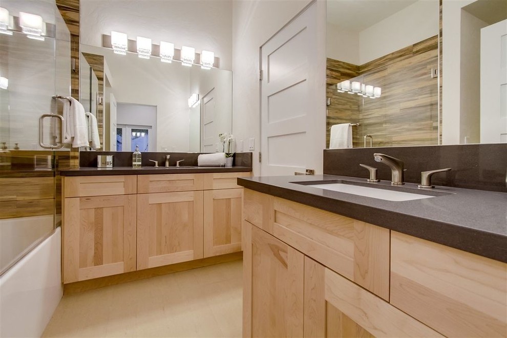 Bathroom - contemporary brown tile and ceramic tile porcelain tile and beige floor bathroom idea in San Diego with shaker cabinets, light wood cabinets, a two-piece toilet, beige walls, an undermount sink, solid surface countertops, a hinged shower door and brown countertops