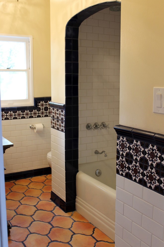 Photo of a medium sized mediterranean bathroom in Orange County with freestanding cabinets, medium wood cabinets, an alcove bath, an alcove shower, a two-piece toilet, multi-coloured tiles, ceramic tiles, white walls, terracotta flooring, a submerged sink and engineered stone worktops.