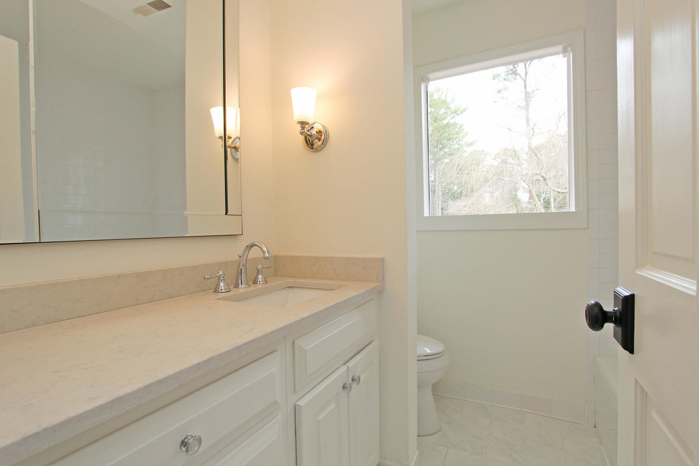 Modern inredning av ett mellanstort badrum, med släta luckor, vita skåp, ett fristående badkar, vita väggar, klinkergolv i keramik och ett undermonterad handfat