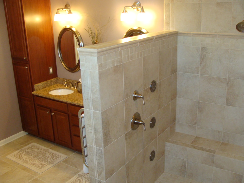 Cette image montre une grande salle de bain principale minimaliste en bois brun avec un lavabo encastré, un placard avec porte à panneau encastré, un plan de toilette en granite, une douche d'angle, un carrelage beige, un carrelage de pierre, un mur beige et un sol en carrelage de porcelaine.