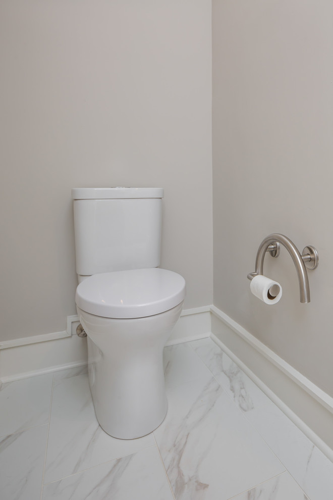 Klassisk inredning av ett stort toalett, med släta luckor, grå skåp, en toalettstol med separat cisternkåpa, vit kakel, keramikplattor, grå väggar, klinkergolv i keramik, ett undermonterad handfat och bänkskiva i kvarts