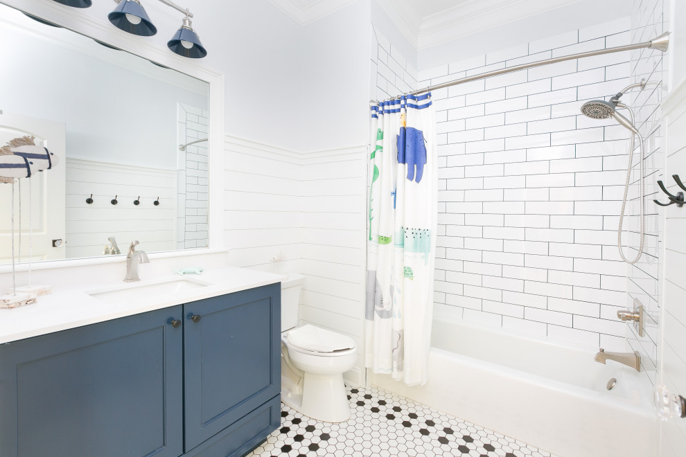 Foto på ett vit badrum för barn, med skåp i shakerstil, blå skåp, ett platsbyggt badkar, en dusch/badkar-kombination, en toalettstol med separat cisternkåpa, vit kakel, keramikplattor, beige väggar, klinkergolv i keramik, ett undermonterad handfat, bänkskiva i kvarts, vitt golv och dusch med duschdraperi