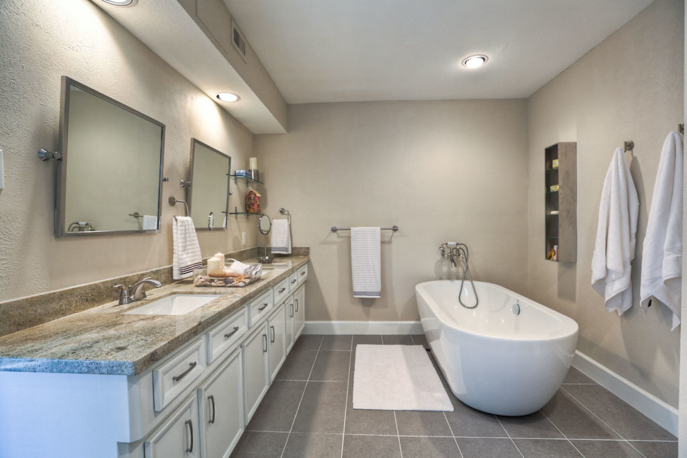 Ejemplo de cuarto de baño clásico renovado con bañera exenta, puertas de armario blancas, armarios con paneles empotrados, paredes grises, lavabo bajoencimera, suelo negro y encimeras grises