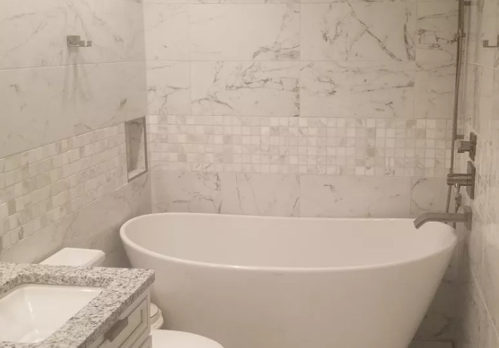 Exempel på ett mellanstort modernt grå grått en-suite badrum, med en toalettstol med hel cisternkåpa, vita väggar, luckor med upphöjd panel, vita skåp, ett fristående badkar, grå kakel, vit kakel, marmorkakel, marmorgolv, ett undermonterad handfat, granitbänkskiva och vitt golv