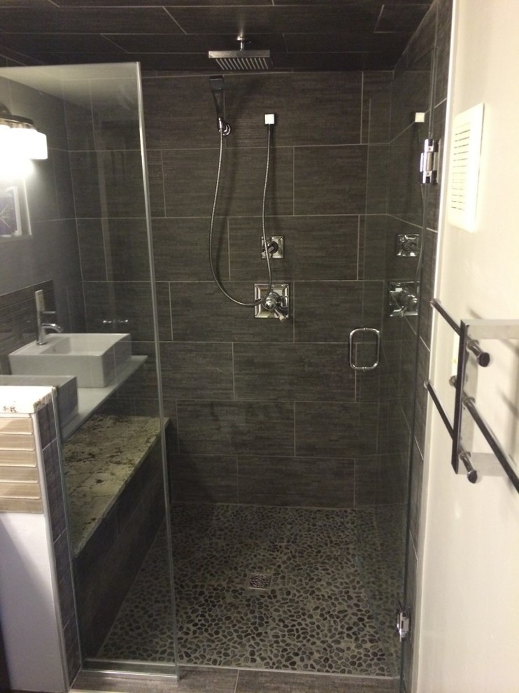 Inspiration för ett badrum, med ett fristående handfat, vita skåp, bänkskiva i akrylsten, en kantlös dusch, svart kakel, stenkakel, svarta väggar och klinkergolv i småsten
