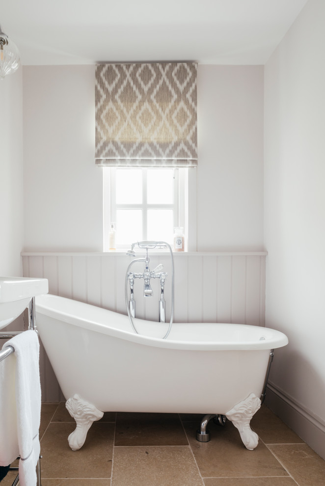 Mid-sized elegant master limestone floor and beige floor freestanding bathtub photo in Cornwall with white walls