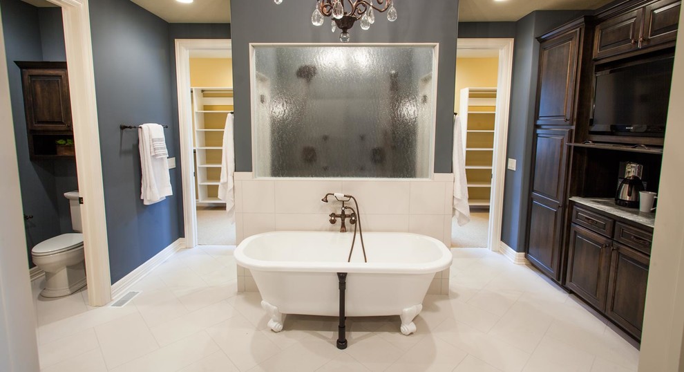 Klassisk inredning av ett stort en-suite badrum, med skåp i mörkt trä, granitbänkskiva, ett fristående badkar, en dubbeldusch, en toalettstol med separat cisternkåpa, vit kakel, porslinskakel, blå väggar och klinkergolv i porslin