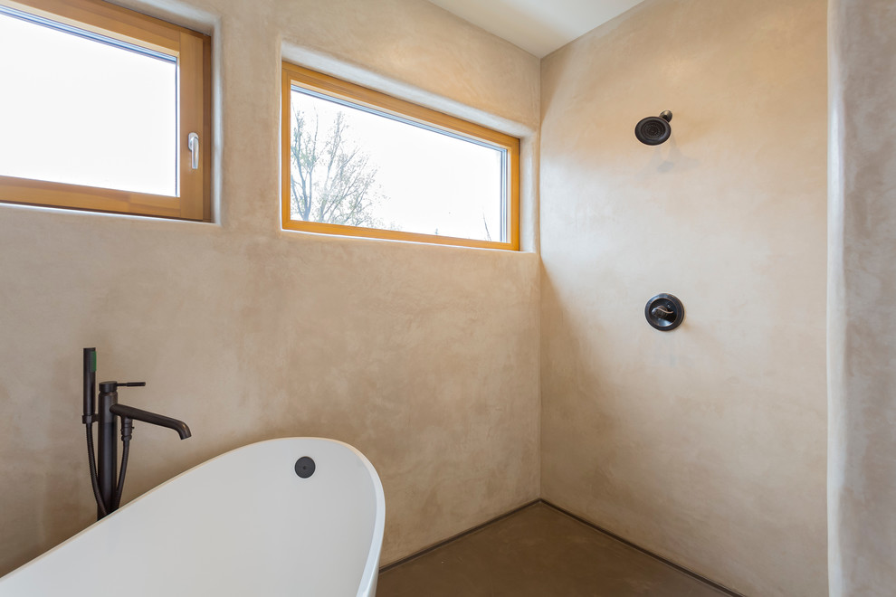На фото: ванная комната среднего размера в средиземноморском стиле с отдельно стоящей ванной, бежевыми стенами, бетонным полом и душевой кабиной