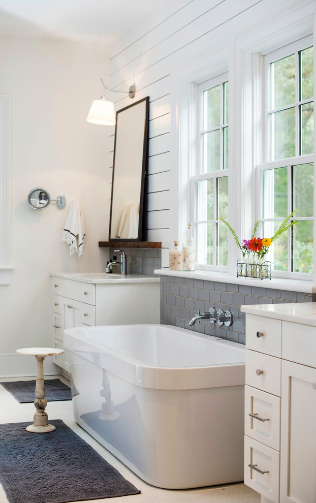 Design ideas for a farmhouse ensuite bathroom in Charlotte with a submerged sink, white cabinets, a freestanding bath, grey tiles and metro tiles.