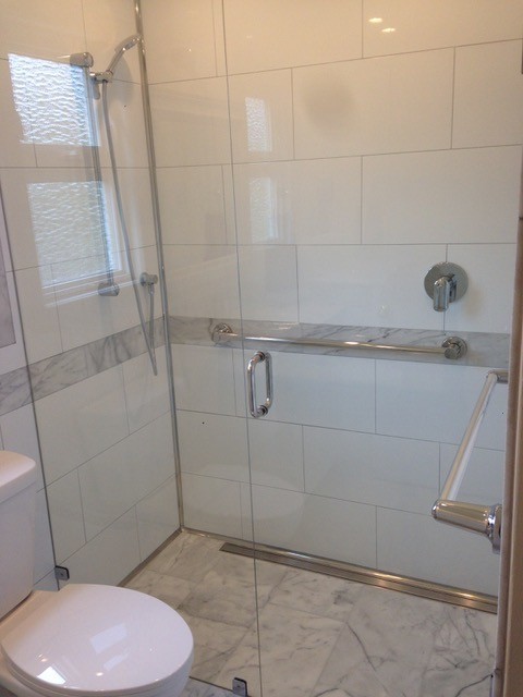 Amerikansk inredning av ett litet badrum, med möbel-liknande, skåp i mellenmörkt trä, ett badkar med tassar, våtrum, en vägghängd toalettstol, marmorgolv, ett undermonterad handfat, marmorbänkskiva och med dusch som är öppen