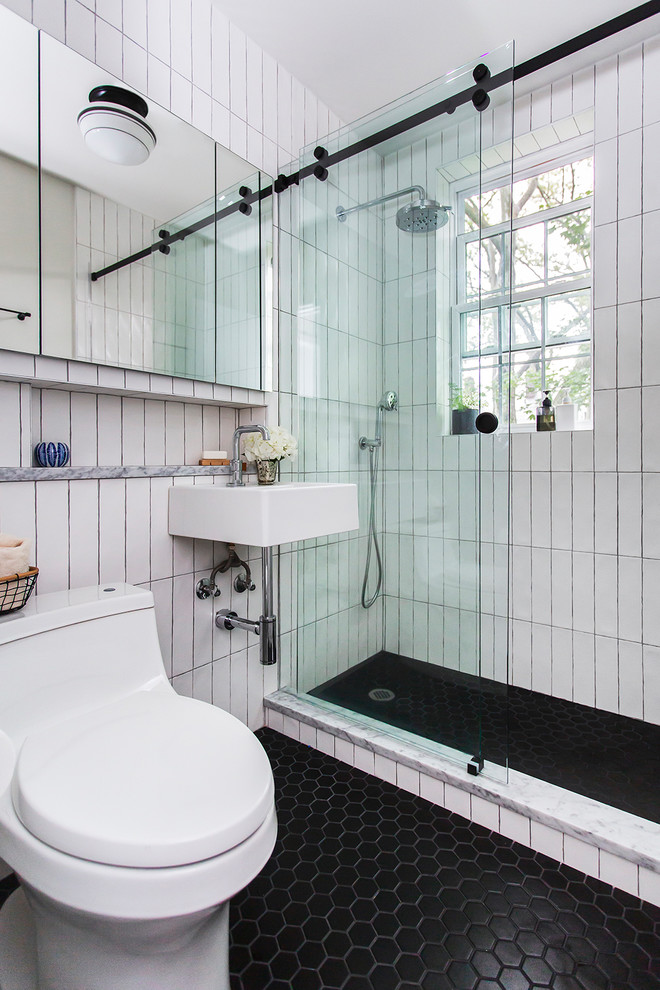 Idee per una stanza da bagno contemporanea con doccia ad angolo, WC monopezzo, piastrelle bianche, pareti bianche, pavimento con piastrelle a mosaico, lavabo sospeso, pavimento nero e porta doccia scorrevole