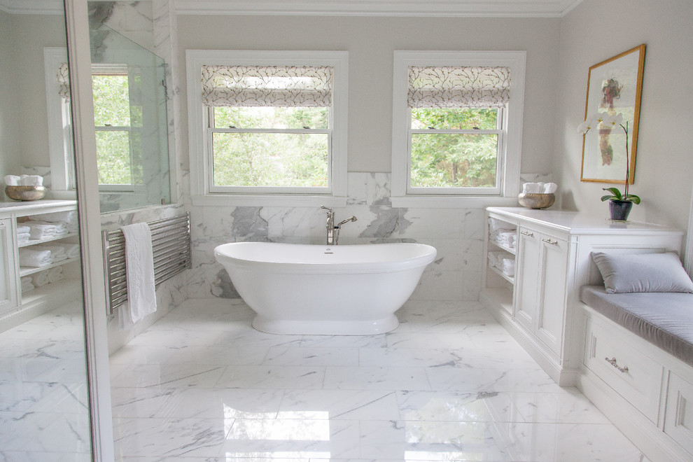 Exemple d'une très grande salle de bain principale chic avec un placard à porte plane, des portes de placard blanches, un plan de toilette en marbre, une baignoire sur pieds, une douche d'angle, un carrelage blanc, un carrelage de pierre, un mur beige et un sol en marbre.