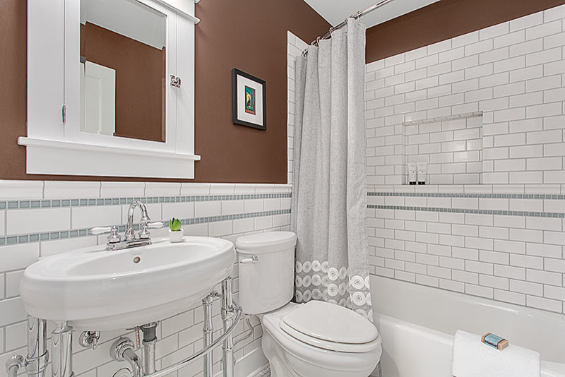 Design ideas for a classic bathroom in Seattle with a shower/bath combination, a one-piece toilet, white tiles, porcelain tiles, brown walls and a wall-mounted sink.