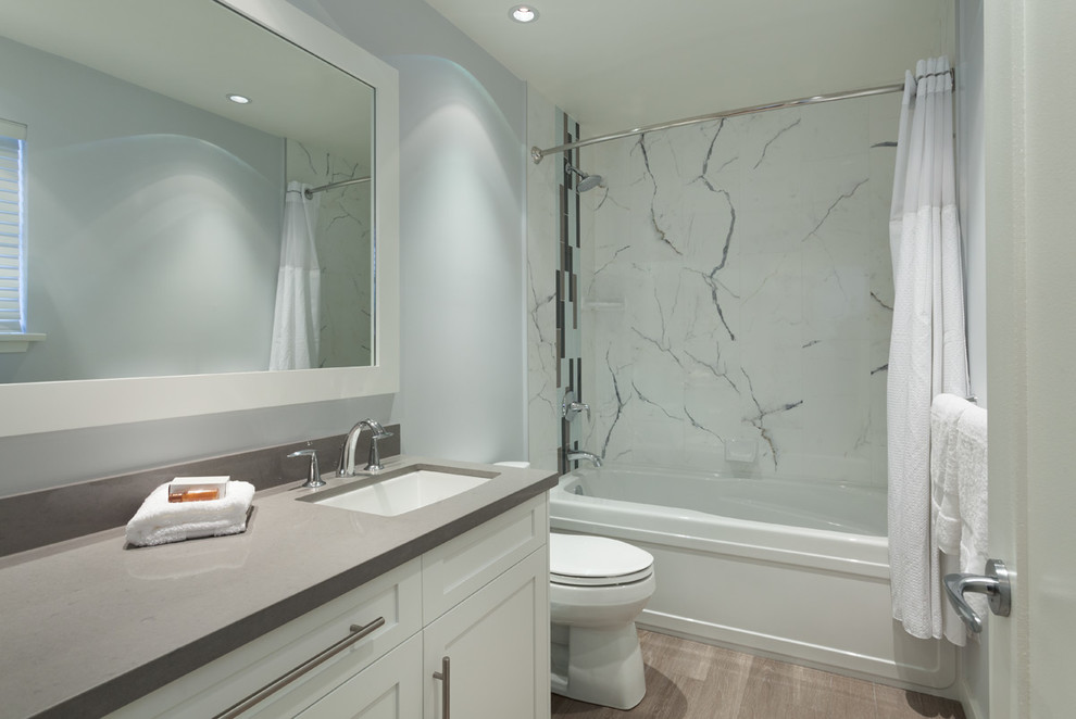 Photo of a medium sized contemporary family bathroom in Vancouver with a submerged sink, shaker cabinets, white cabinets, engineered stone worktops, an alcove bath, a shower/bath combination, a two-piece toilet, white tiles, porcelain tiles, grey walls and porcelain flooring.