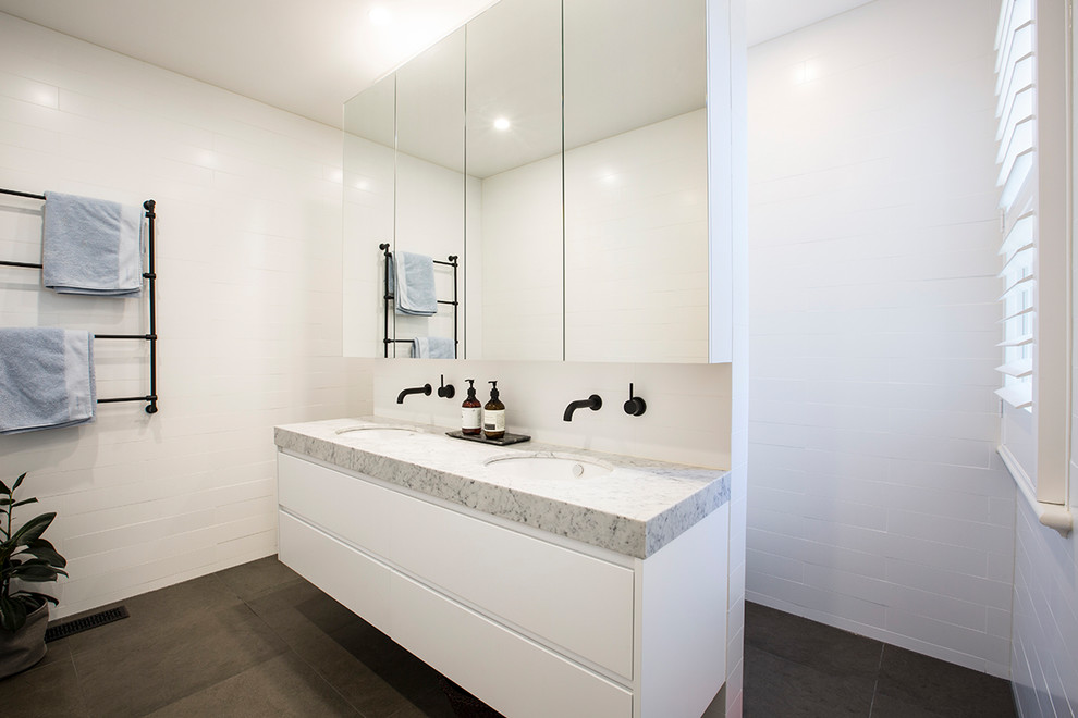 Foto di una stanza da bagno design con ante lisce, ante bianche, doccia aperta, pareti bianche, lavabo sottopiano, pavimento grigio e doccia aperta
