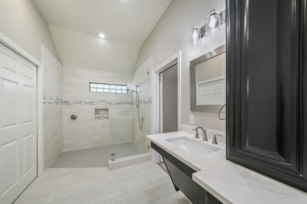 Bild på ett mellanstort funkis vit vitt en-suite badrum, med luckor med upphöjd panel, vita skåp, en kantlös dusch, en bidé, grå kakel, keramikplattor, grå väggar, klinkergolv i keramik, ett undermonterad handfat, bänkskiva i kvarts, grått golv och med dusch som är öppen