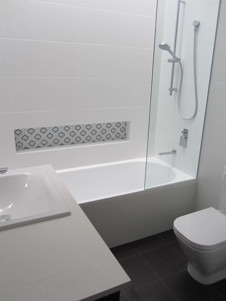 This is an example of a small modern bathroom in Sydney with a built-in sink, engineered stone worktops, an alcove bath, a shower/bath combination, white tiles, ceramic tiles, white walls and ceramic flooring.