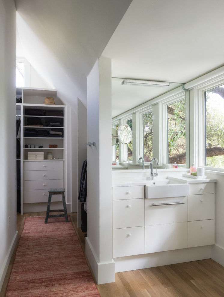 Idées déco pour une salle de bain contemporaine avec un placard à porte plane, des portes de placard blanches, un mur beige, un sol en bois brun et un lavabo posé.