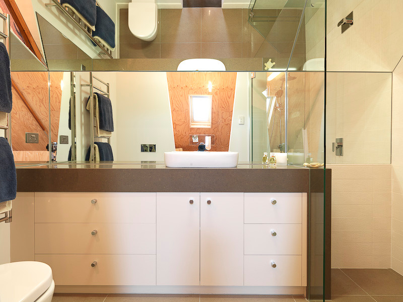 Exempel på ett litet modernt en-suite badrum, med ett fristående handfat, släta luckor, vita skåp, bänkskiva i kvarts, en dusch i en alkov, en vägghängd toalettstol, beige kakel, porslinskakel, vita väggar och klinkergolv i porslin