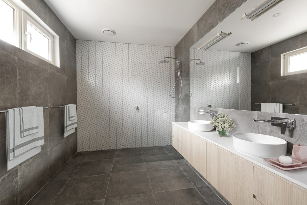 Modelo de cuarto de baño doble y flotante minimalista con armarios con paneles lisos, puertas de armario de madera clara, lavabo sobreencimera, suelo gris y encimeras blancas