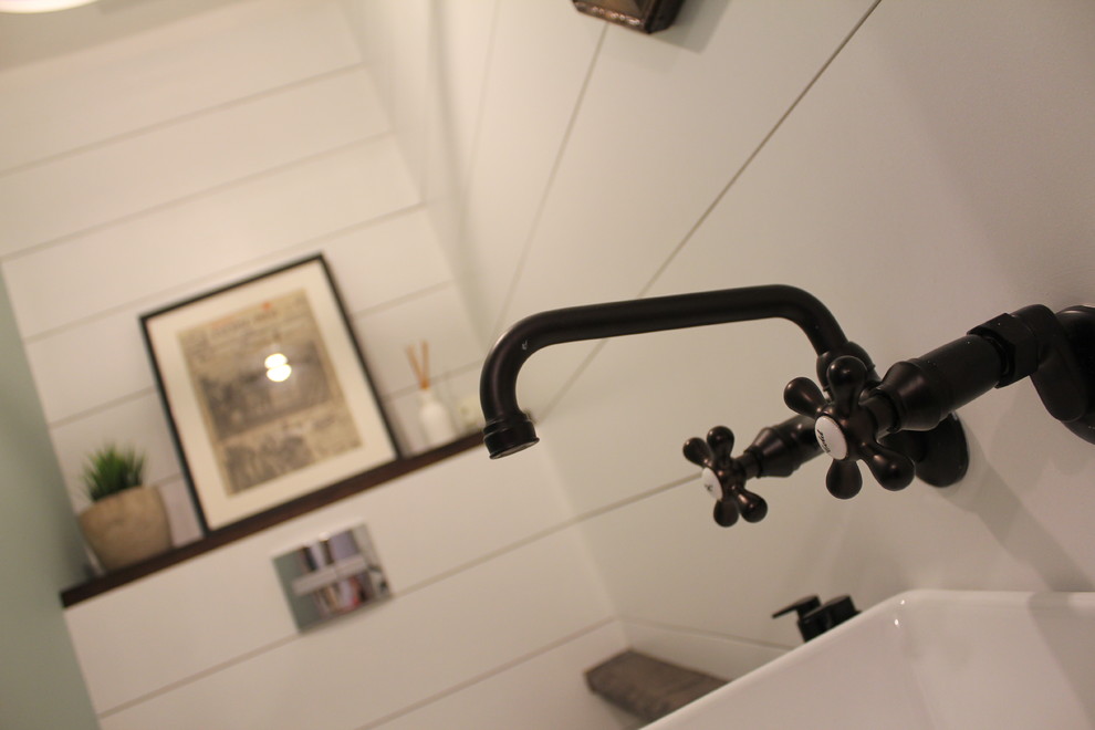 Foto de cuarto de baño de estilo de casa de campo pequeño con sanitario de pared, paredes blancas, suelo de madera clara, lavabo de seno grande y encimera de madera