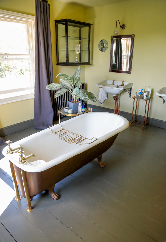 Aménagement d'une salle de bain campagne avec une baignoire indépendante, un mur vert, parquet foncé, un lavabo suspendu et un sol marron.