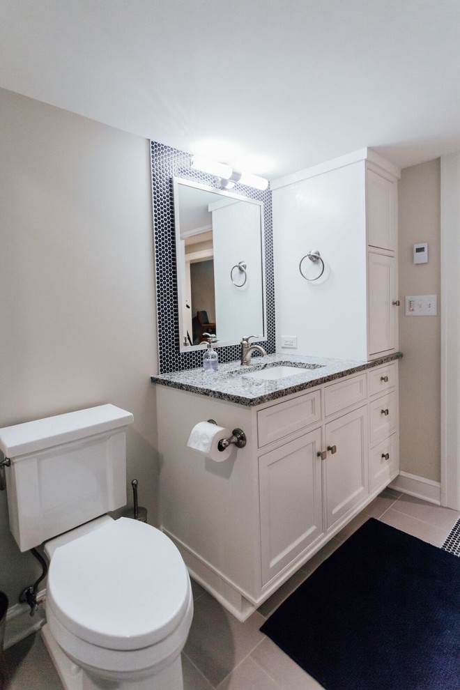 Cette image montre une salle de bain traditionnelle de taille moyenne avec un placard avec porte à panneau encastré, des portes de placard blanches, WC séparés, un carrelage gris, un carrelage métro, un mur gris, un lavabo encastré et un plan de toilette en granite.