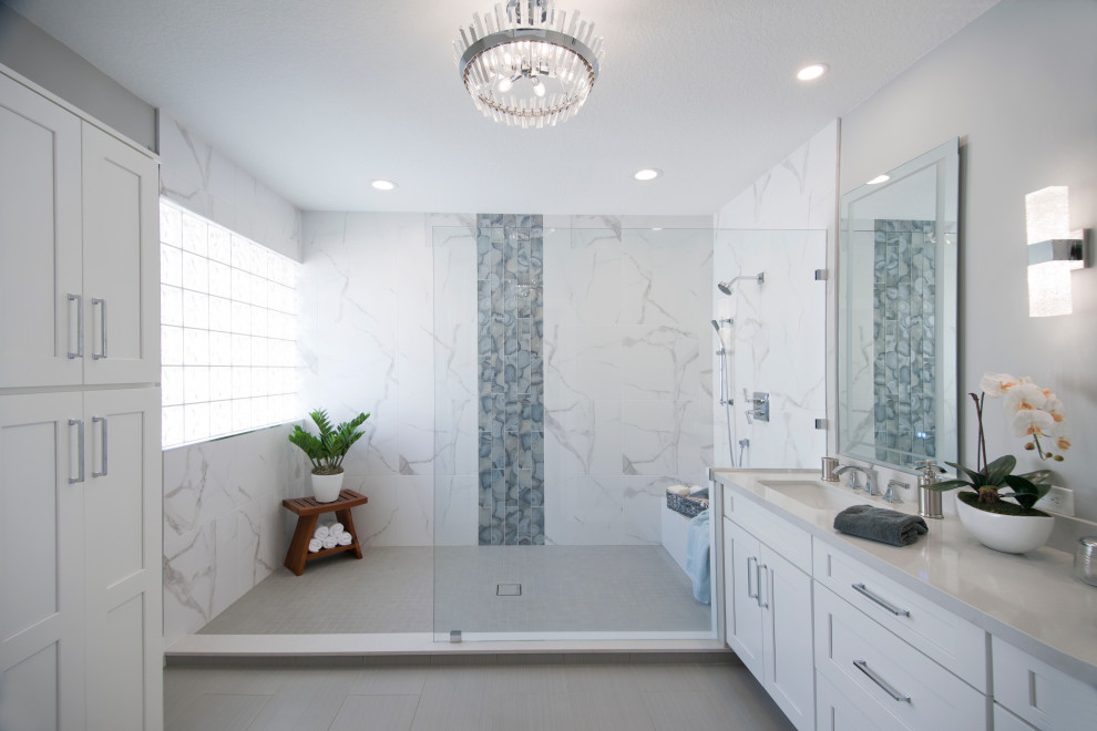 Идея дизайна: большая главная, серо-белая ванная комната в современном стиле с фасадами в стиле шейкер, белыми фасадами, открытым душем, раздельным унитазом, белой плиткой, керамогранитной плиткой, серыми стенами, полом из керамогранита, врезной раковиной, столешницей из искусственного кварца, серым полом, серой столешницей, акцентной стеной, тумбой под две раковины и встроенной тумбой