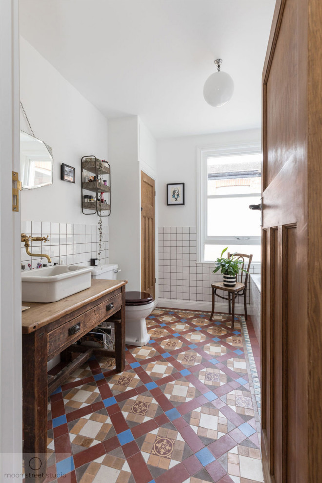 Пример оригинального дизайна: детская ванная комната среднего размера в современном стиле с плоскими фасадами, коричневыми фасадами, накладной ванной, угловым душем, унитазом-моноблоком, белой плиткой, керамической плиткой, белыми стенами, полом из керамической плитки, настольной раковиной, столешницей из дерева, душем с распашными дверями, коричневой столешницей, тумбой под одну раковину и напольной тумбой