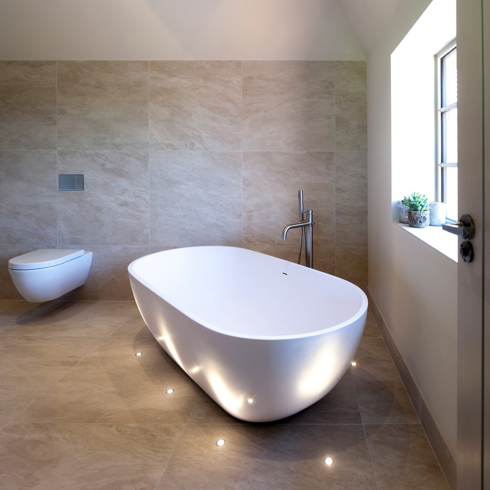 Cette image montre une grande salle de bain principale design en bois clair avec un placard à porte plane, une baignoire indépendante, une douche ouverte, WC suspendus, un carrelage beige, des carreaux de céramique, un mur blanc et un sol en carrelage de céramique.
